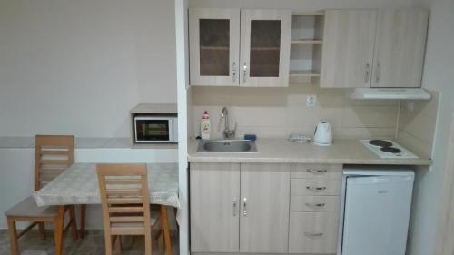 a small kitchen with white cabinets and a table and chairs at Ubytovanie v sukromi Haragova in Bojnice