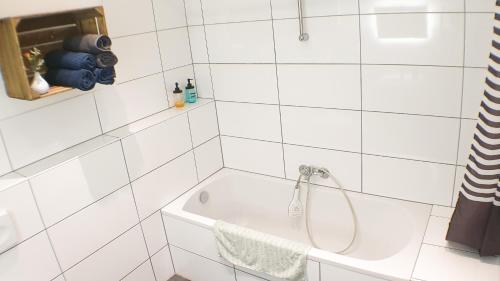 a white tiled bathroom with a shower and a tub at Big Appartment near trade fair! in Cologne