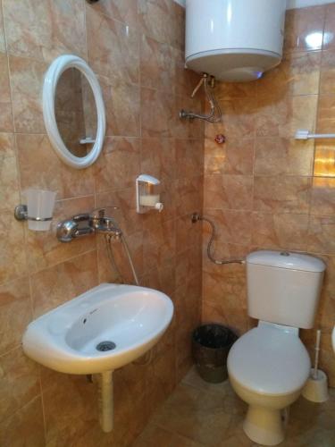 a bathroom with a sink and a toilet and a mirror at East Gate Guest Rooms in Plovdiv
