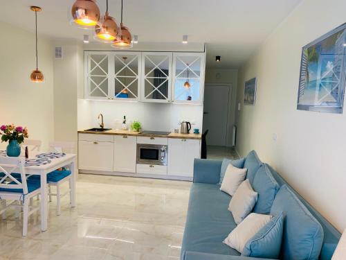 a living room with a blue couch and a kitchen at Apartament Jantarowe Zacisze Blue in Jantar