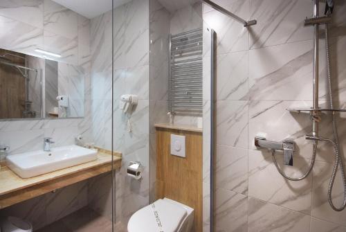 e bagno con doccia, servizi igienici e lavandino. di Hotel Dobru a Slănic-Moldova