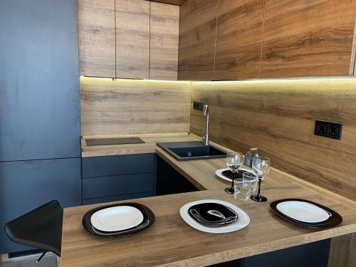 eine Küche mit einem Waschbecken und einem Holztisch mit Tellern und Gläsern in der Unterkunft New Coast Apartaments Odessa near sea in Odessa