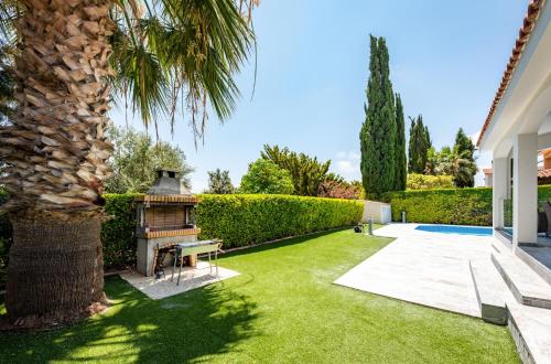 a garden with a palm tree and a grill at Bungalow Mikaella by Ezoria Villas in Coral Bay