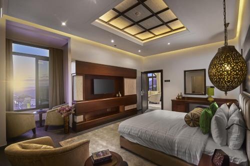 a bedroom with a bed and a tv and a couch at Sahab Resort and Spa, Jabal Al Akhdar in Al ‘Aqar