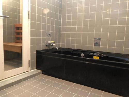 a bathroom with a black tub and a mirror at Hotel Civic Inn Sayama in Sayama