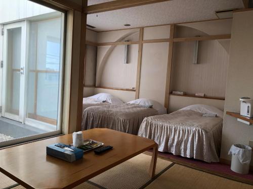 Zimmer mit 2 Betten, einem Tisch und einem Fenster in der Unterkunft Hotel Civic Inn Sayama in Sayama