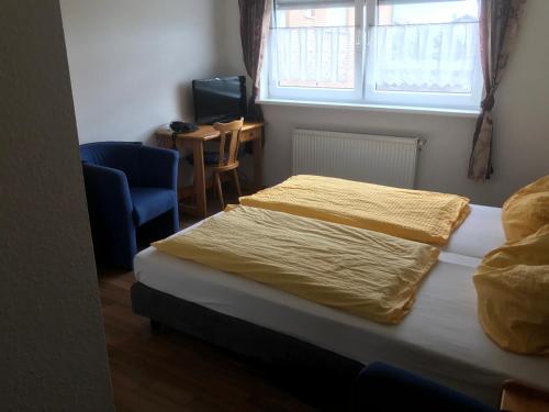 a bedroom with a bed and a chair and a window at Hotel Kaufmann in Rommerskirchen