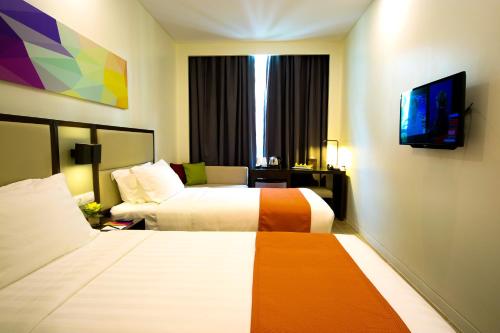 マニラにあるHotel Lucky Chinatownのベッド2台とテレビが備わるホテルルームです。
