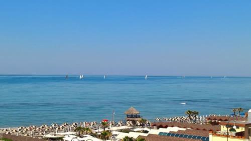 einen Strand mit einem Haufen Stühle und dem Meer in der Unterkunft Hotel La Scaletta in Lido di Ostia