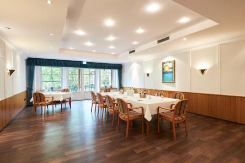 a dining room with white tables and chairs at Brackstedter Mühle e.K. in Wolfsburg