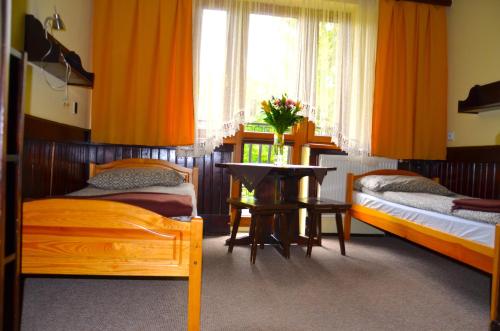 a bedroom with two beds and a table in it at Ośrodek Wypoczynkowo-Szkoleniowy HALNY in Zawoja