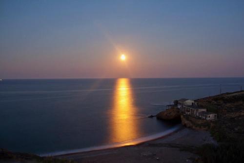 a sunset over the ocean with the sun setting on the water at Unique Anoi House - In the Heart of Skyros Village in Skiros