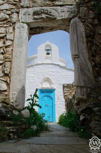 a white church with a blue door and a steeple at Unique Anoi House - In the Heart of Skyros Village in Skiros