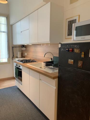 a kitchen with white cabinets and a black refrigerator at Big Bright New Apt next to Casino in Monte Carlo