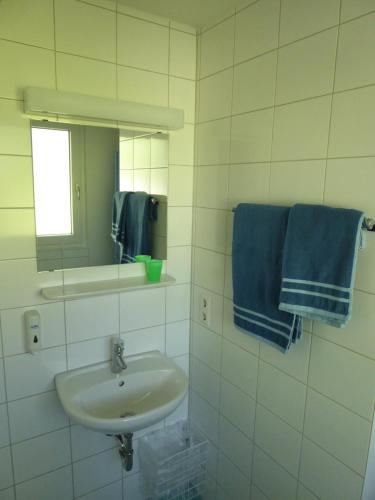 ein Badezimmer mit einem Waschbecken, einem Spiegel und blauen Handtüchern in der Unterkunft Topp Apartments in Tübingen