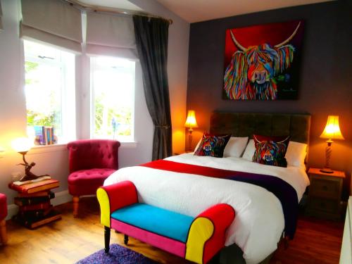 a bedroom with a large bed and a chair at Angel Cottage in Drymen