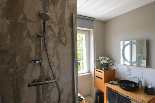 a bathroom with a shower with a sink and a mirror at Entre Terre et Mer in Plougoulm