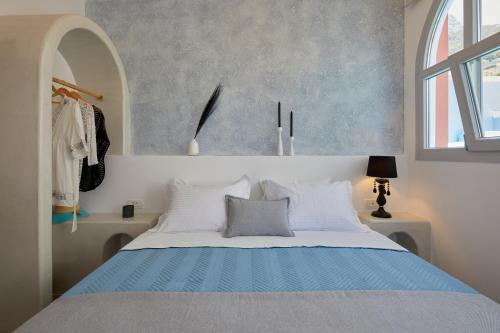a bedroom with a blue and white bed with a window at Blue Sea Hotel in Kamari