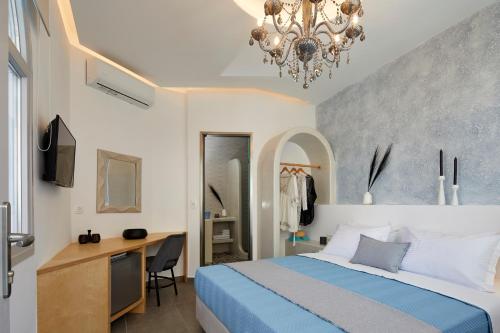 a bedroom with a bed and a desk and a chandelier at Blue Sea Hotel in Kamari