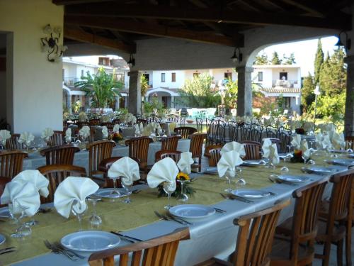 une grande table avec des chaises, des assiettes et des serviettes dans l'établissement Hotel Domu Incantada, à Muravera