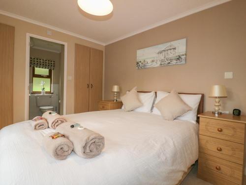 a bedroom with a white bed with towels on it at Crocus Lodge in Bodmin