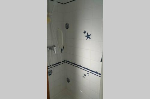 une salle de bain avec douche carrelée de blanc dans l'établissement Maison de pêcheur, à Grandcamp-Maisy