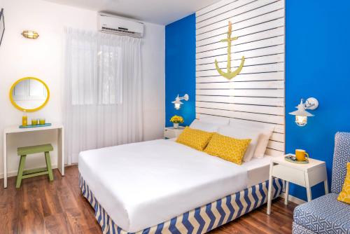 1 dormitorio con cama blanca y pared azul en Travel Hotel Gesher Haziv en Gesher HaZiw