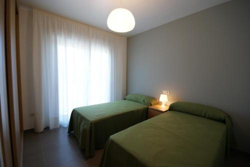 duas camas num quarto de hotel com uma janela em Apartamentos Mirador de Reis em Sanxenxo