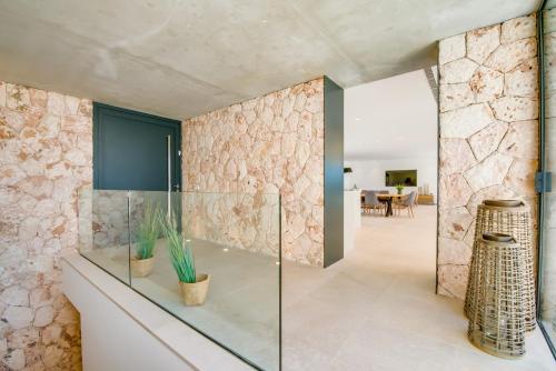 een glazen douche in een badkamer met een stenen muur bij Pura Vida in Ariany