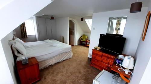 a bedroom with a bed and a television in it at Le Chene Hotel in St Peter Port