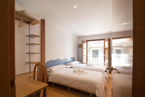 1 dormitorio con 3 camas, mesa y ventana en Pucela apartmets en Valladolid