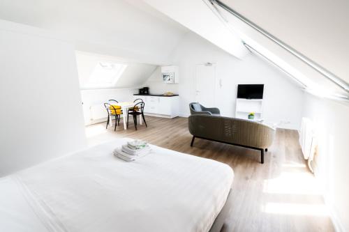 Habitación blanca con cama y sala de estar. en FLATS - Résidence D'ici D'ailleurs en Bruselas
