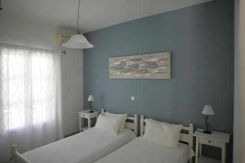 a bedroom with two beds and a window with a painting at Villa Sophie in Naousa