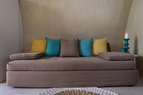 a couch with colorful pillows on it in a room at Mythical Blue Luxury Suites in Fira