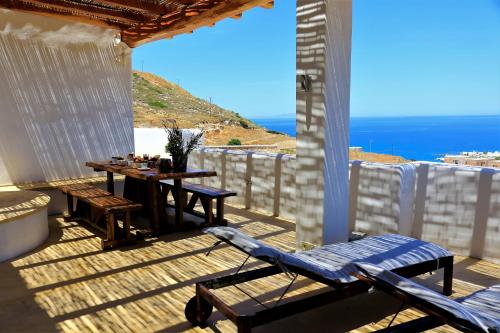 a wooden deck with a table and a view of the ocean at Aegean Blue Houses in Mandrakia