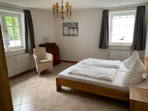 Schlafzimmer mit einem Bett, einem Stuhl und Fenstern in der Unterkunft Villa Friedericia - Appartment 1 in Wyk auf Föhr