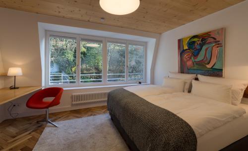 1 dormitorio con cama, ventana y silla roja en Zweite Heimat Heidelberg en Heidelberg