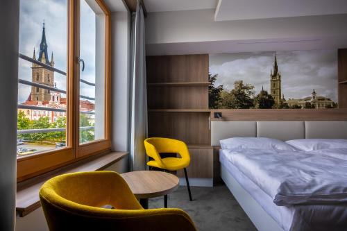 1 Schlafzimmer mit einem Bett, 2 Stühlen und einem Fenster in der Unterkunft Hotel Grand in Čáslav