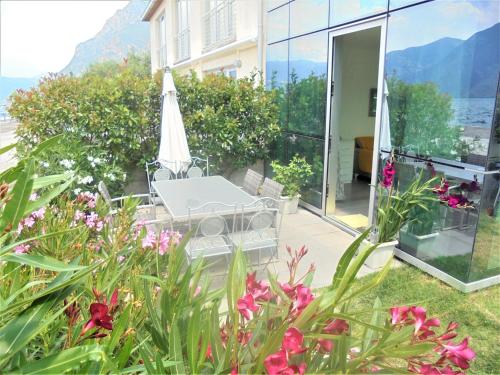 a patio with a table and an umbrella and flowers at Dock House in Marone