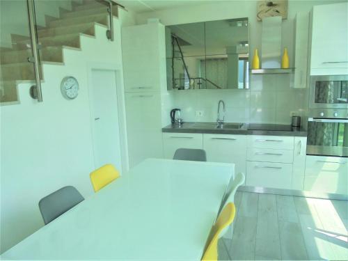 a white kitchen with a white table and chairs at Dock House in Marone