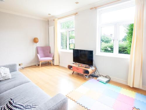 een woonkamer met een bank en een flatscreen-tv bij Modern & Peaceful Family Home with Private Garden in Londen