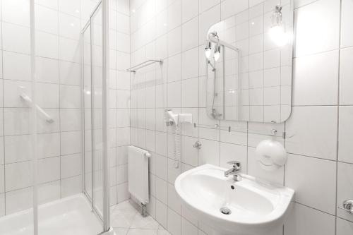 a white bathroom with a sink and a shower at Hotel Jan Sander in Aleksandrów Łódzki