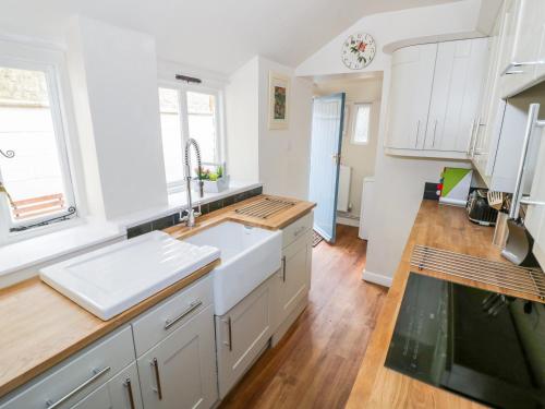 eine Küche mit weißen Schränken und einer Spüle in der Unterkunft Victoria Cottage in Chipping Norton