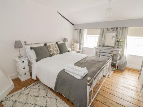 a bedroom with a white bed and a television at Thimble Cottage in Cheltenham