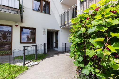 a building with a large green bush next to a walkway at Apartments Platynowa Gdańsk by Renters in Gdańsk