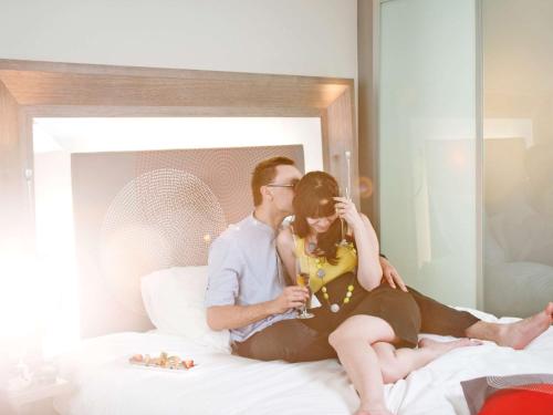 a man and a woman sitting on a bed at Novotel Chennai OMR in Chennai