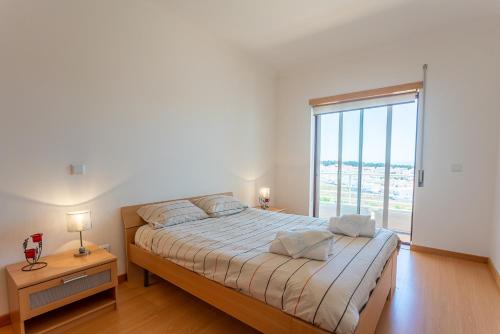 a bedroom with a bed and a large window at T2 Branquinho in Nazaré