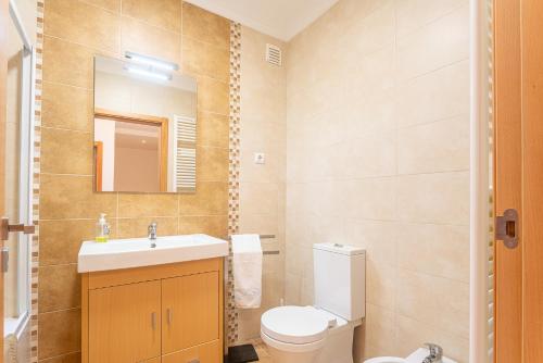 a bathroom with a sink and a toilet and a mirror at T2 Branquinho in Nazaré