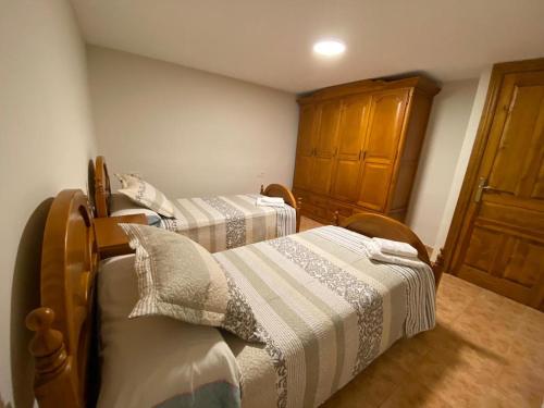 a bedroom with two beds and a wooden cabinet at CASA PEDRO BERGUA in Fiscal
