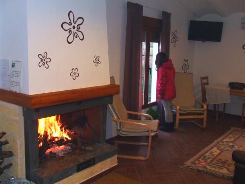 a woman standing in a living room with a fireplace at Vivienda Rural Embalse San Clemente in Huéscar